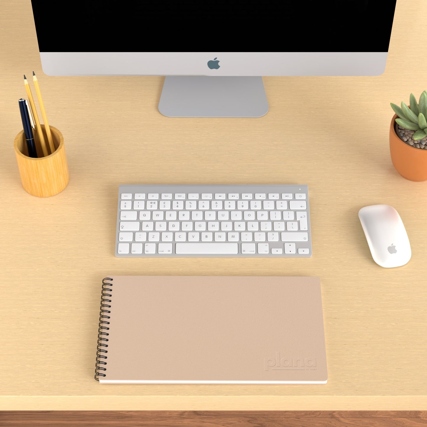 Plana Classic Blush on a wooden desk with a computer, pen holder, and plant