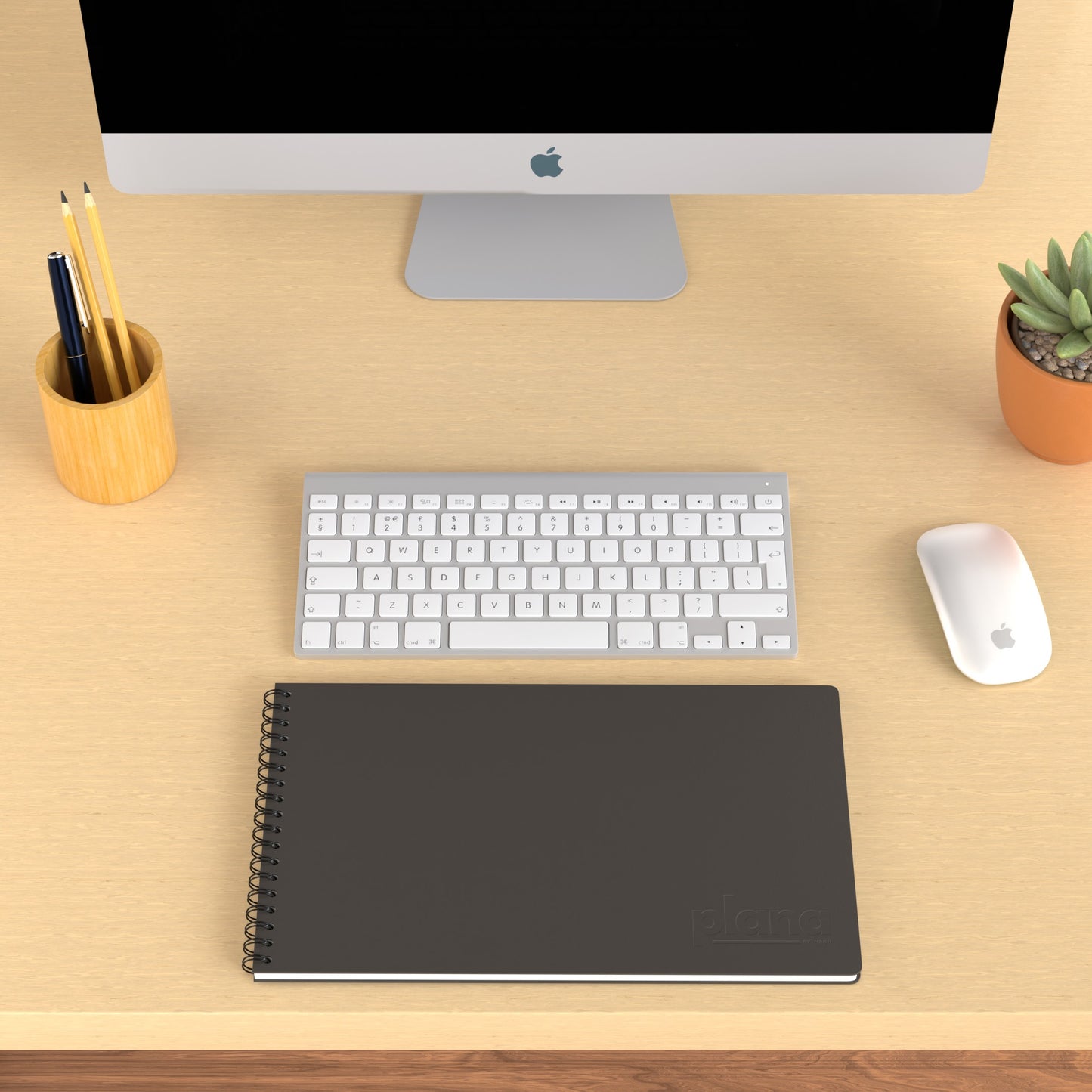 Plana Pro Graphite on a wooden desk with a computer, pen holder, and plant