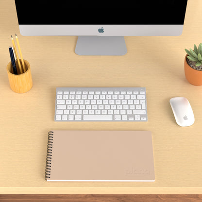 Plana Classic Blush on a wooden desk with a computer, pen holder, and plant