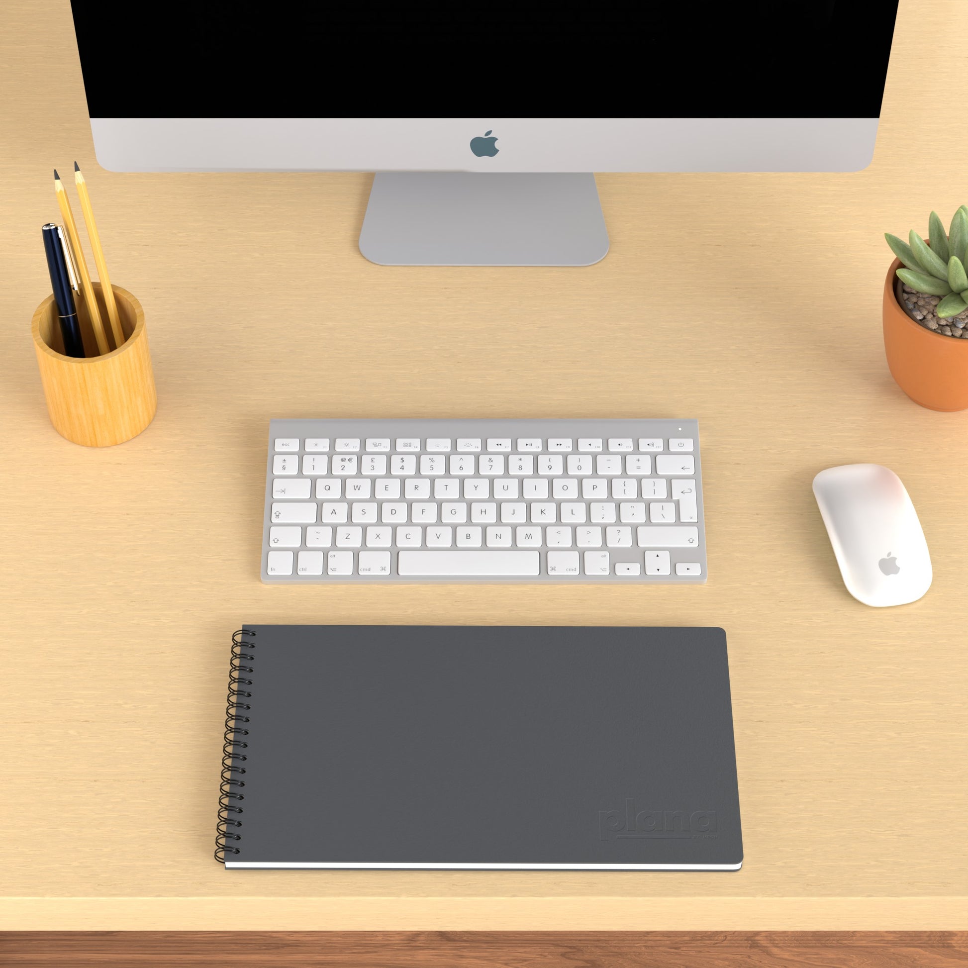 Plana Classic Stone on a wooden desk with a computer, pen holder, and plant
