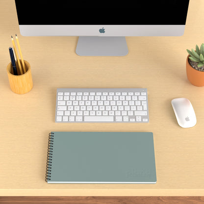 Plana Classic Tide on a wooden desk with a computer, pen holder, and plant