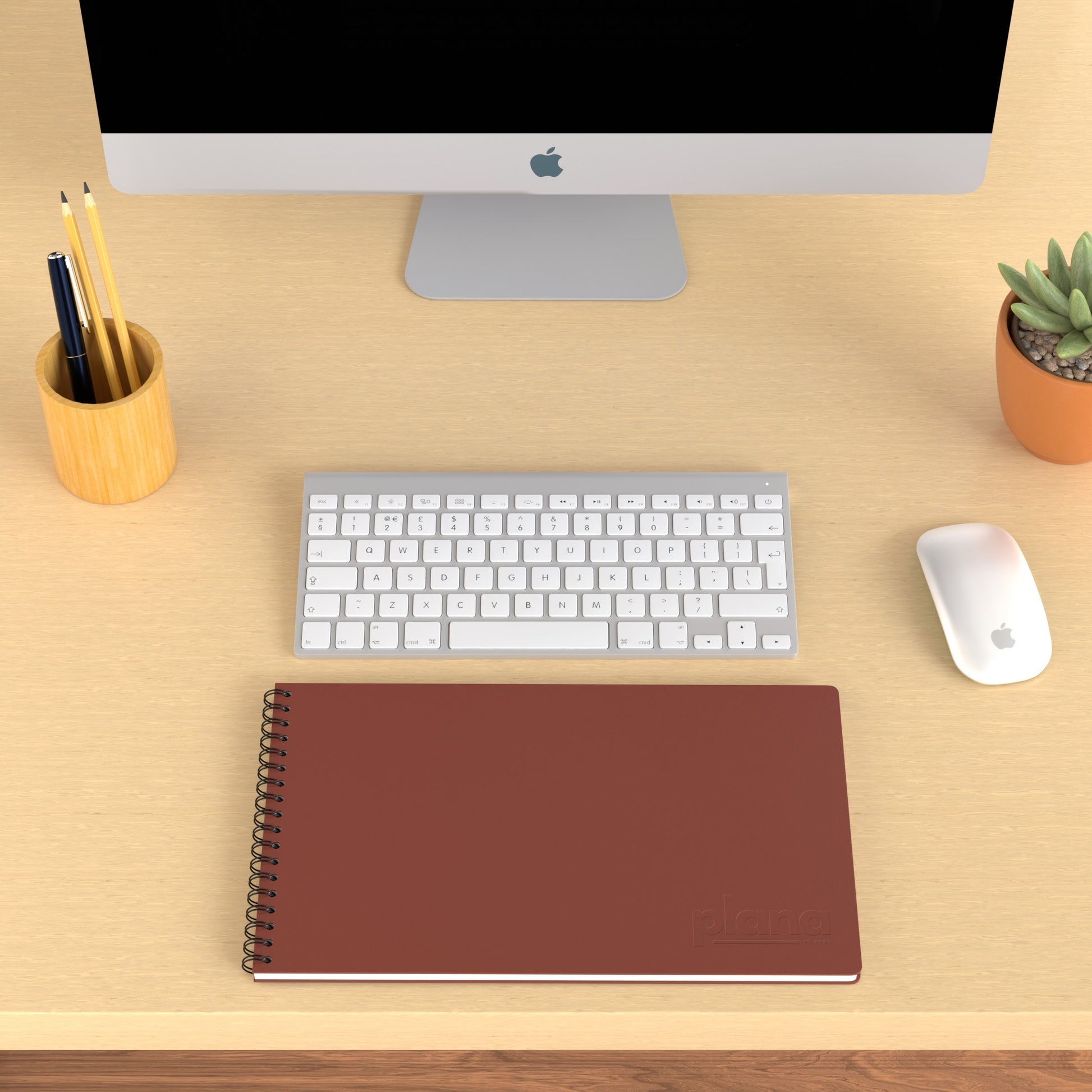 Plana Pro Garnet on a wooden desk with a computer, pen holder, and plant